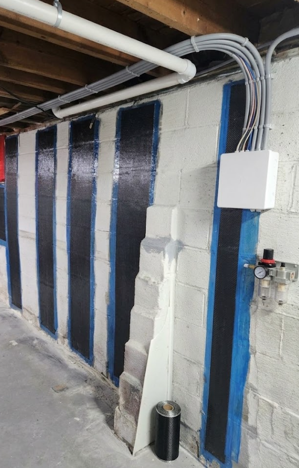 Carbon fiber straps installed vertically on a cinder block basement wall to reinforce against hydrostatic pressure